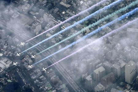 　カラースモークを出して東京都心上空を飛行する航空自衛隊の「ブルーインパルス」＝２４日