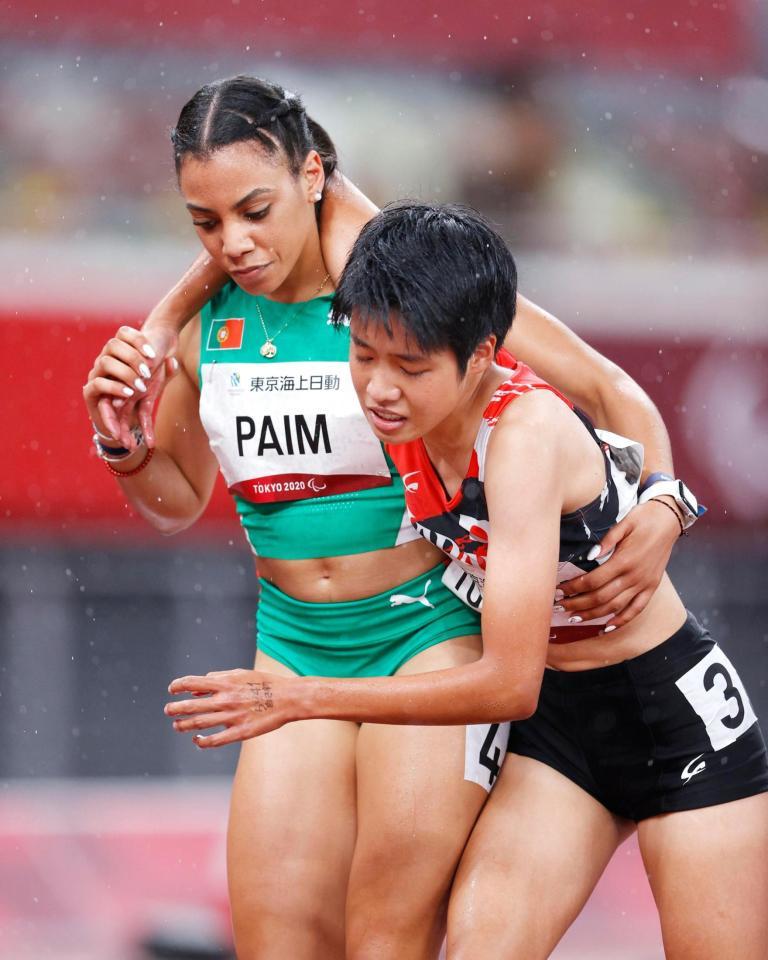 　女子４００メートル（知的障害）決勝のレースを終え、ポルトガル選手に支えられながら引き揚げる外山愛美（右）