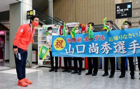 　松山空港で勤務先の四国ガス社員らに出迎えられ、お辞儀をする競泳男子１００メートル平泳ぎ金メダリストの山口尚秀選手＝２日午後