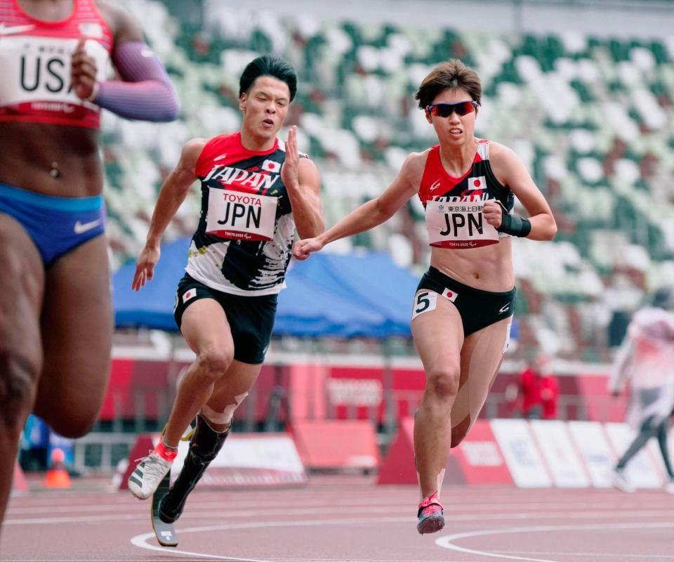 　４００メートルユニバーサルリレー予選　第２走者の大島健吾（左）から第３走者の高松佑圭へリレー＝国立競技場