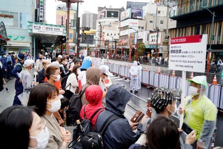 　東京パラリンピックのマラソンコース周辺で、観戦自粛の案内を掲げる関係者と集まった大勢の人たち＝５日午前、東京・浅草