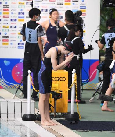 　女子１００メートルバタフライ決勝で２着となりスタンドに向かって手を合わせて頭を下げる池江璃花子。後方は優勝インタビューを受ける飯塚千遥（撮影・開出牧）