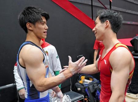 　男子個人総合決勝の演技終了後、握手を交わす橋本大輝（左）と中国の張博恒（代表撮影）