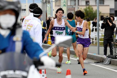 ７区を１位で通過した駒沢大の田沢廉（左）は最終走者の花尾恭輔にタスキを渡す＝代表撮影