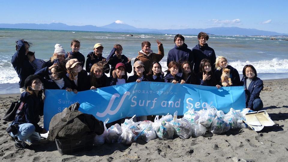 　ビーチクリーン活動に参加し、富士山と海をバックに写真に応じる（後列右から３番目の）大原洋人ら