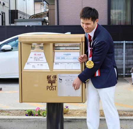 　出身地に設置された金色の郵便ポストに触れる木村敬一