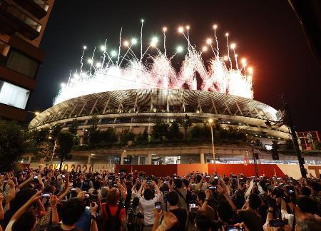 　東京五輪の閉会式で、国立競技場から打ち上げられたフィナーレの花火を路上で見上げる大勢の人たち＝８月