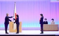 　北京冬季オリンピックの日本選手団の結団式で、秋篠宮さまご夫妻が見守る中、団旗を伊東団長（左）から受け取る郷亜里砂旗手（左から２人目）。同３人目は高木美帆主将（代表撮影）