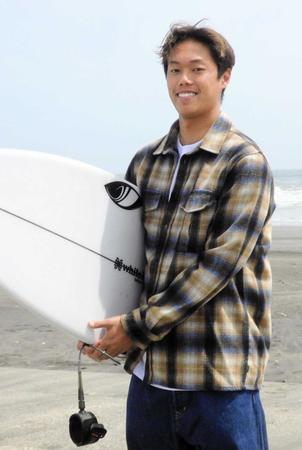 　サーフボードを持ち、笑顔で写真撮影に応じる上山キアヌ久里朱