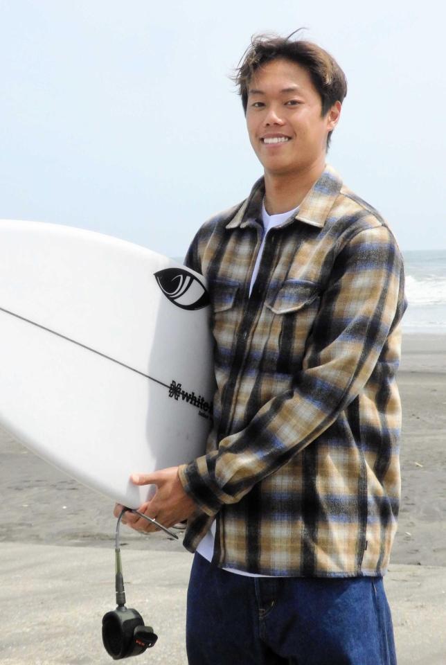　サーフボードを持ち、笑顔で写真撮影に応じる上山キアヌ久里朱
