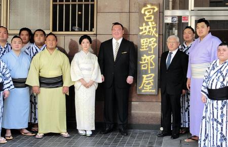 　部屋の看板の前で記念撮影する宮城野親方（中央）ら