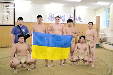 　ダーニャ（中央）とともにウクライナ国旗を持つ山中新大（後列左から２人目）ら関大相撲部員