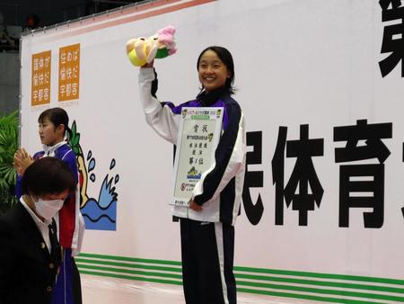 　表彰台で笑顔を見せる成田実生