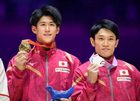 　体操の世界選手権男子個人総合で、初優勝を果たし金メダルを手にする橋本大輝（左）と銅メダルの谷川航（共同）