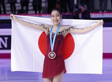 　女子で初優勝し、日の丸を広げる三原舞依（共同）