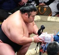 　ぶ厚い懸賞金の束を手にする貴景勝