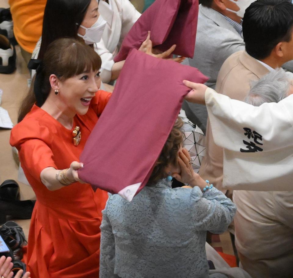 　土俵に投げ込まれた座布団が当たり、右ほほを押さえるデヴィ夫人（中央）＝撮影・伊藤笙子
