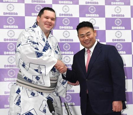 　雷親方（右）と握手をする新十両の獅司（撮影・佐々木彰尚）