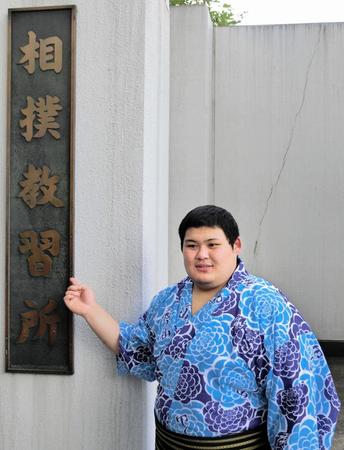 　相撲教習所の看板の前でポーズをとる大の里