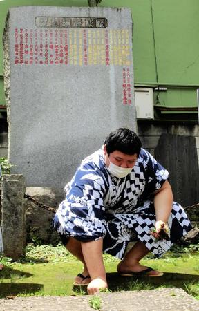 　歴代横綱のしこ名が刻まれた石碑の前で草をむしる大の里