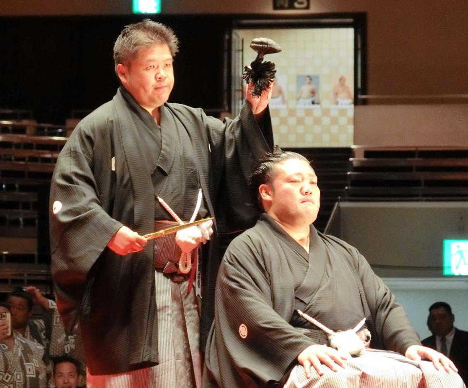 　師匠の時津風親方（左）に止めばさみを入れられ、万感の表情を浮かべる元幕内豊山の小柳亮太氏