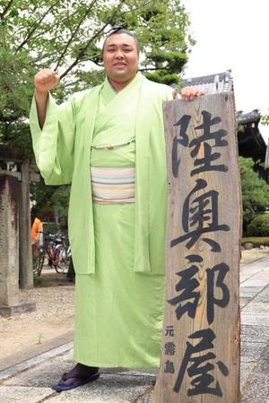 　陸奥部屋の立て看板を手にポーズをとる霧島