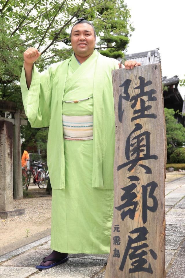 　陸奥部屋の立て看板を手にポーズをとる霧島