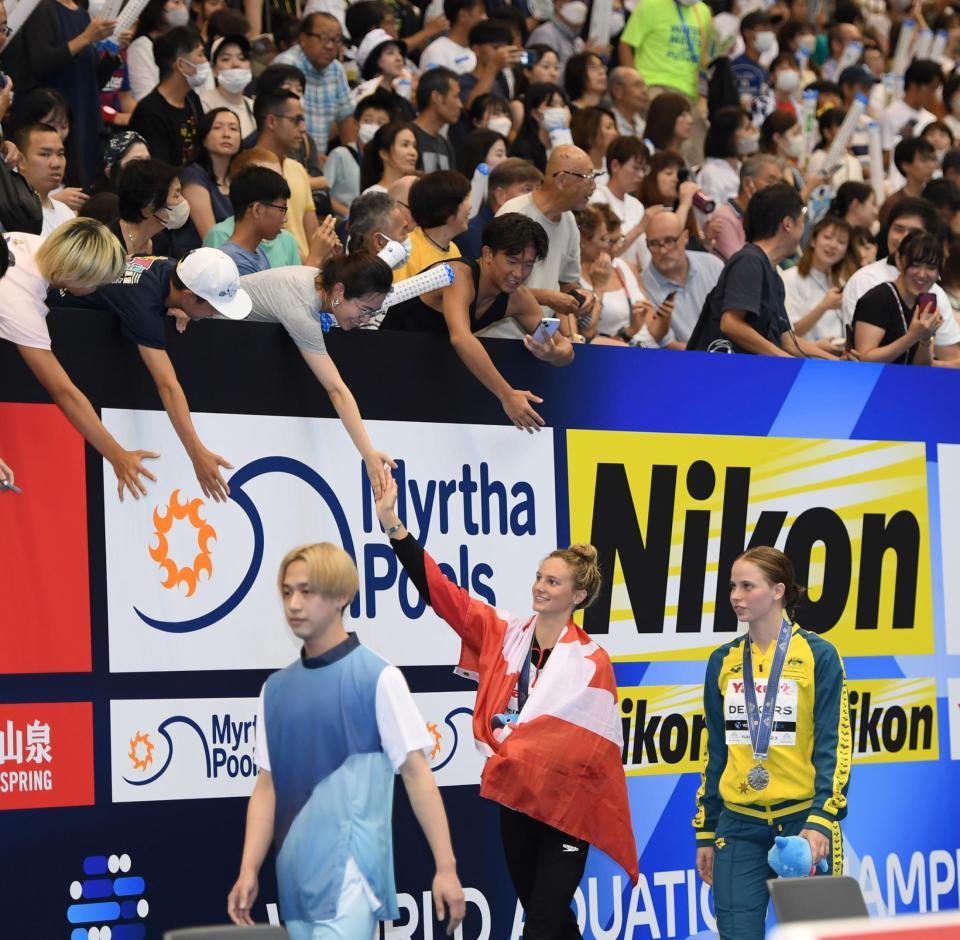 　女子２００メートルバタフライ決勝で金メダルを獲得したサマー・マッキントッシュ（中央下）はスタンドのファンと握手をする（撮影・中田匡峻）