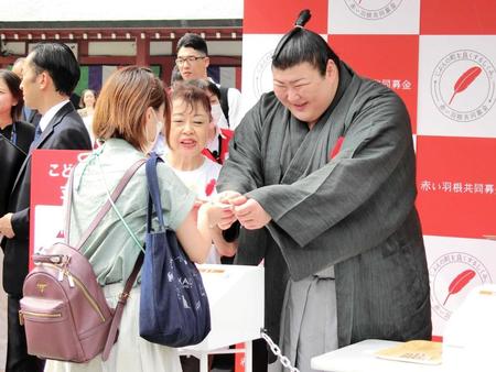 　赤い羽根共同募金運動のキックオフイベントで、募金者に羽根を手渡す熱海富士（右）