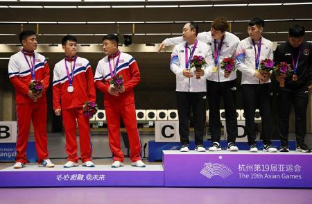 　射撃の表彰式で銀メダルの北朝鮮チーム（左）が金メダルの韓国チームと並んで写真を撮られることを拒否する一幕があった＝９月２５日、中国・杭州（ロイター＝共同）