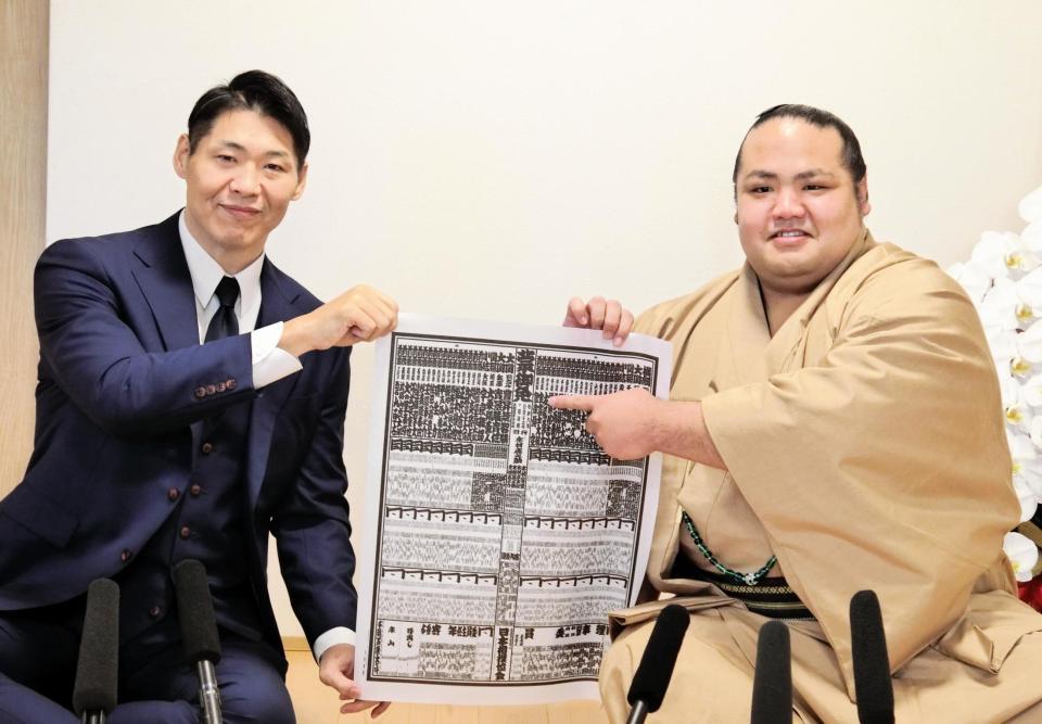 　新入幕を果たし、笑顔で番付のしこ名を指さす島津海（右）と師匠の放駒親方