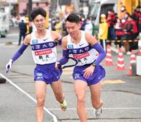 　２区の鈴木芽吹からたすきを受け取り駆け出す３区の駒大・佐藤圭汰（撮影・開出牧）