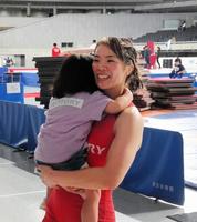 　出産後初の世界切符をつかみ、長女を抱っこして笑顔を見せる金城梨紗子