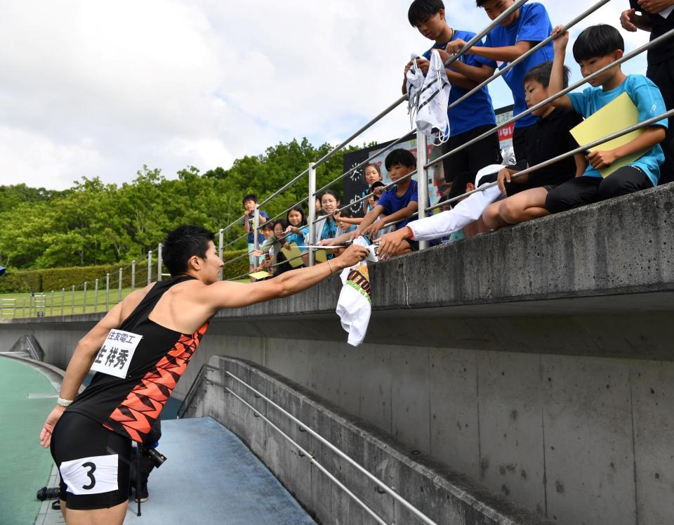 　男子１００メートル決勝を終え、こどもに自身のゼッケンを手渡す桐生祥秀（撮影・中田匡峻）