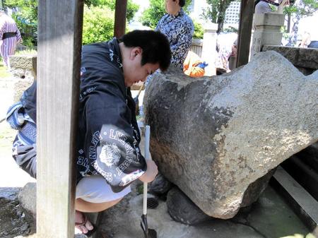 　神社の手水舎（ちょうずしゃ）をほうきで掃く草野