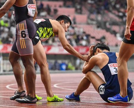 　男子１００メートル決勝を終え、座り込む柳田大輝に声をかける桐生祥秀（左）