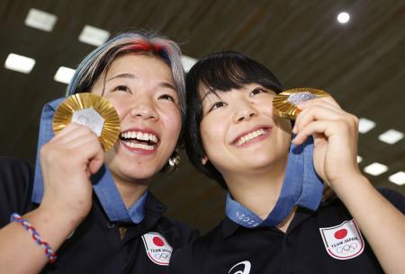 　パリ五輪で獲得した金メダルを手に笑顔を見せる、レスリング女子の藤波朱理（右）と鏡優翔＝１２日、パリ近郊のシャルル・ドゴール空港（共同）