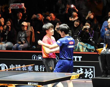 　決勝で世界１位の王楚欽（右）に完敗し、試合後に握手する張本智和