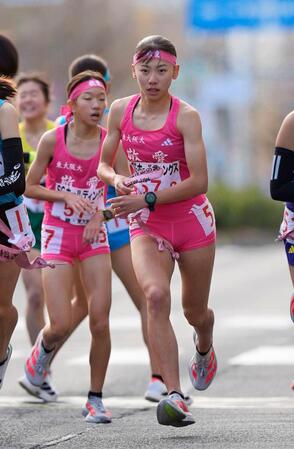 　東大阪大敬愛１区の長谷川結都（左）からたすきを受け取り、走り出す２区の久保凛