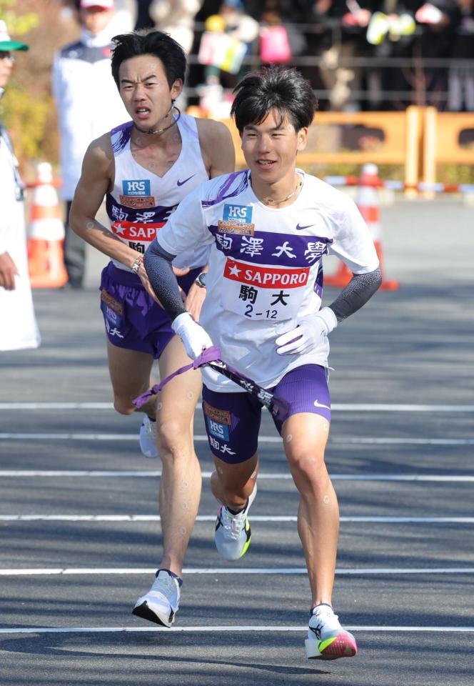 桑田駿介（左）からたすきを受け、スタートする駒大・山川拓馬（撮影・西岡正）