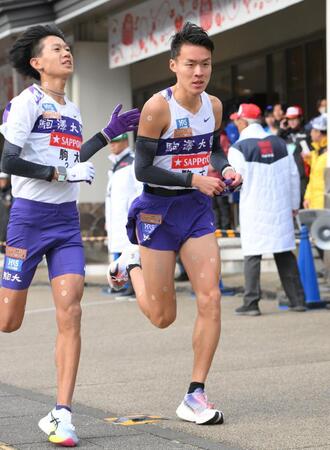 　伊藤蒼唯（左）からたすきを受け取り走り出す駒大・佐藤圭汰（撮影・伊藤笙子）