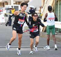 　齊藤大空（左）からたすきを受け駆け出す創価大・吉田響＝２日