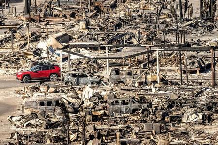 火事で焼失した建物脇を走行する乗用車＝12日、米ロサンゼルス（ＡＰ＝共同）