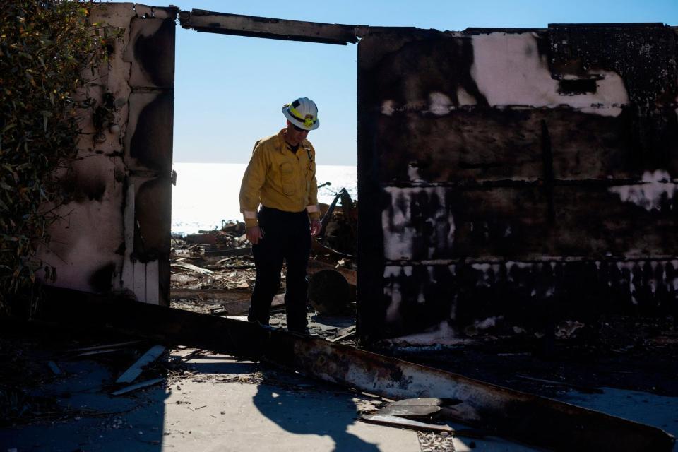 火事の被害を確認する消防隊員＝12日、米ロサンゼルス近郊（ロイター＝共同）