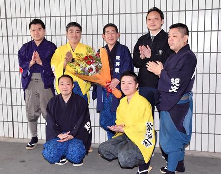 定年を迎え花束を贈られた呼び出しの次郎さん（中央）＝撮影・佐藤厚