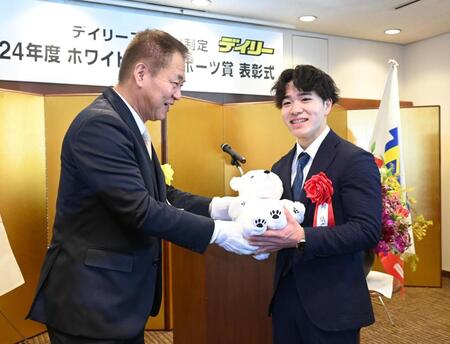 　記念のぬいぐるみをデイリースポーツ・藤谷稔社長（左）から手渡され笑顔を見せる岡慎之助（撮影・園田高夫）