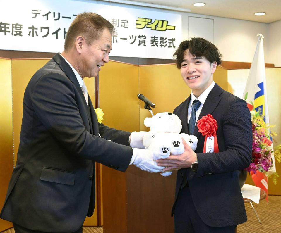 　記念のぬいぐるみをデイリースポーツ・藤谷稔社長（左）から手渡され笑顔を見せる岡慎之助（撮影・園田高夫）