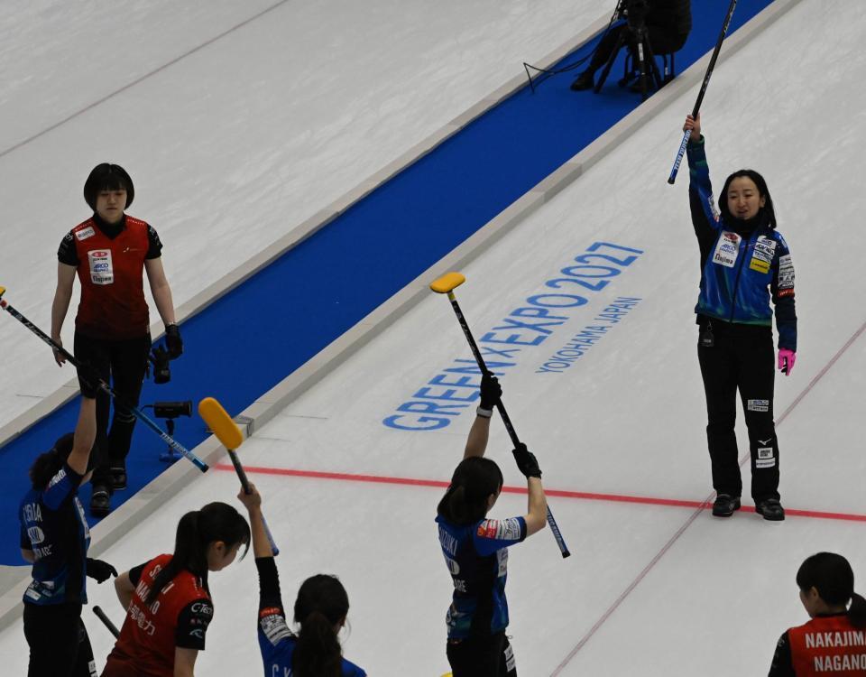 　会心のショットが決まりブラシを高く掲げる藤沢五月（右）らロコ・ソラーレのメンバー（撮影・持木克友）