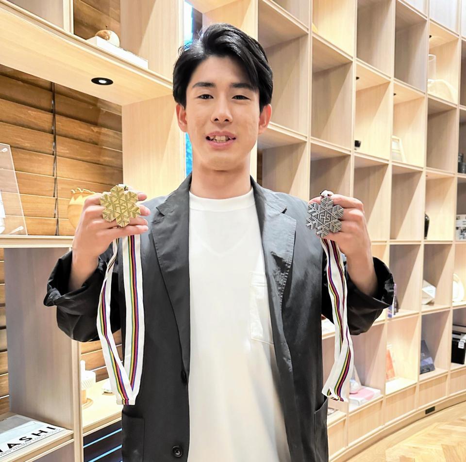 　世界選手権で獲得した金メダルと銀メダルを手に、笑顔を見せる堀島