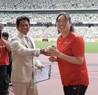 　織田裕二（左）から客席に投げ入れる花束を受け取る北口榛花